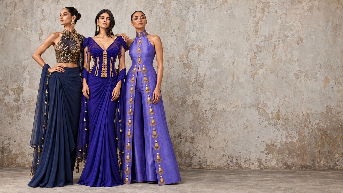 Three models against a weathered plaster wall in navy, cobalt and violet occasion wear with gold hand embroidery
